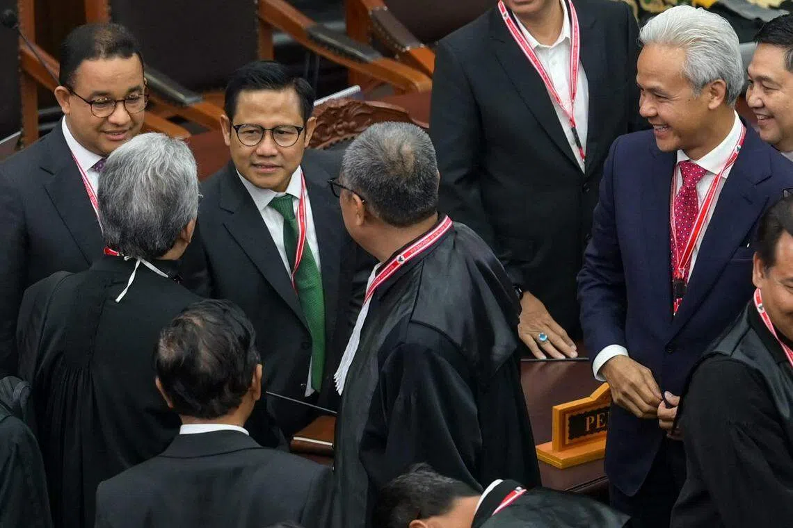 在印尼总统选举中落败的雅加达特区前首长阿尼斯（左一）和副手穆海敏（左二），以及中爪哇省前省长甘查尔（右一）和副手马福德（背对镜头，左下）星期一在宪法法院聆听八司就他们发起的选举诉讼宣读判词。双方和他们的律师团队相互寒暄。（法新社）