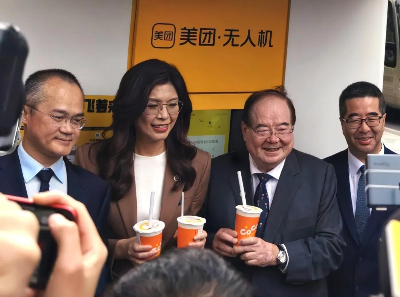 中国国民党主席郑丽文一行星期三（4月8日）下午在上海参观美团公司总部，并体验无人机送餐。图为郑丽文（左二）在美团创始人兼董事长王兴（左一）的陪同下，拿到无人机送来的奶茶。 国民党副主席萧旭岑（右一）、党副主席兼秘书长李乾龙（右二）也陪同参观。（中新社）