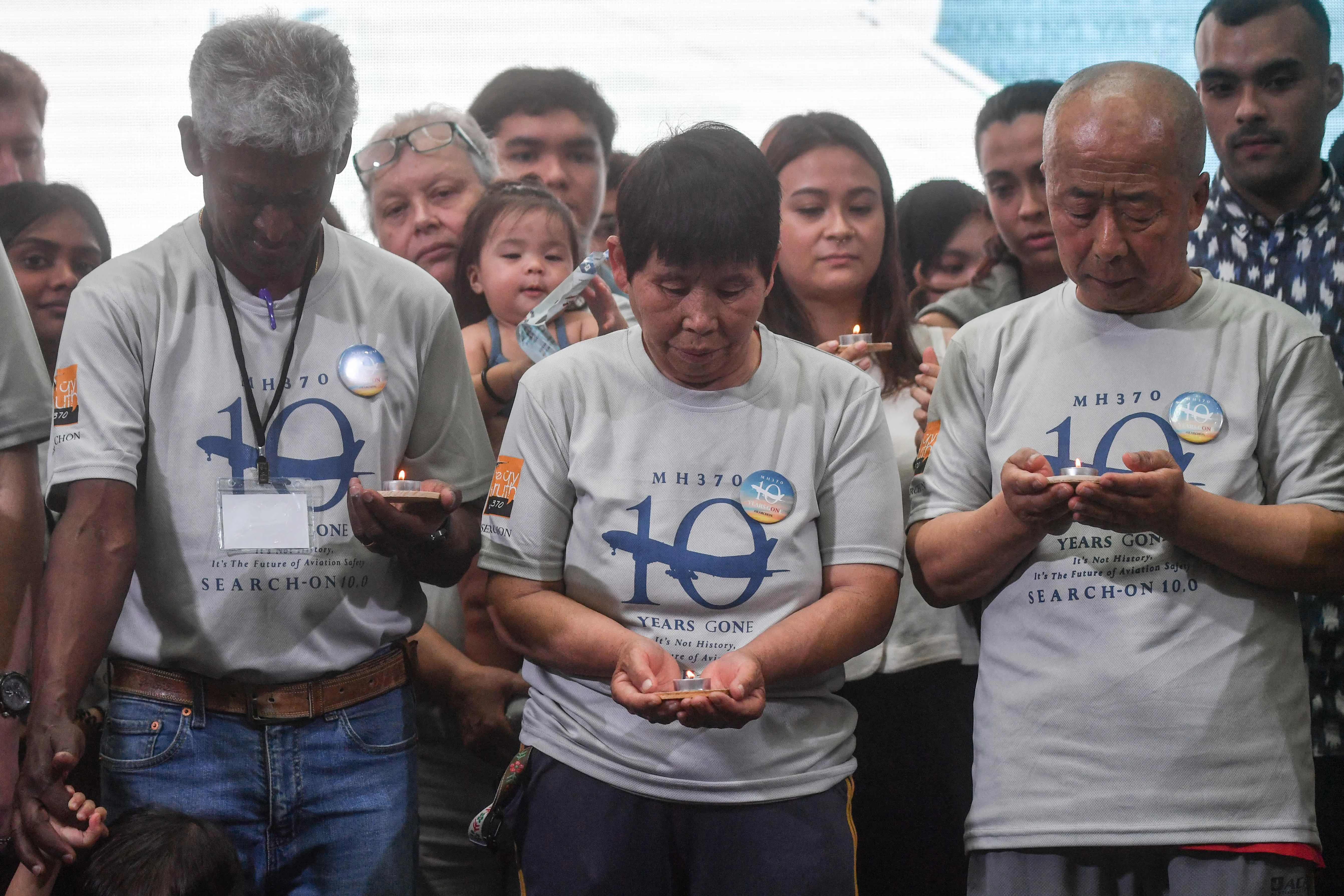 乘客家属手捧烛火，缅怀在MH370事件中逝去的家人。（法新社）