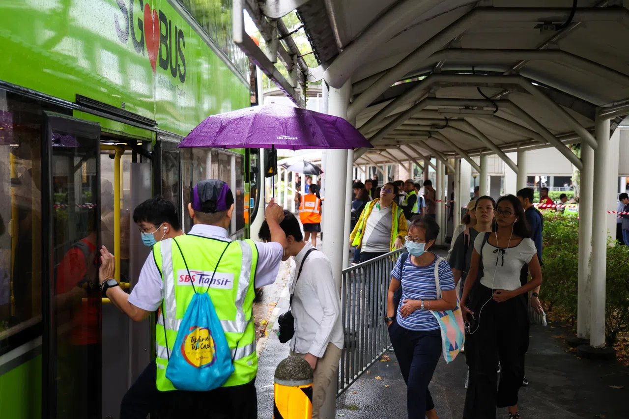 西部地区星期四（9月26日）早上一度阴雨绵绵，工作人员为搭乘接驳巴士的公众撑起伞，暖心十足。（林明顺摄）