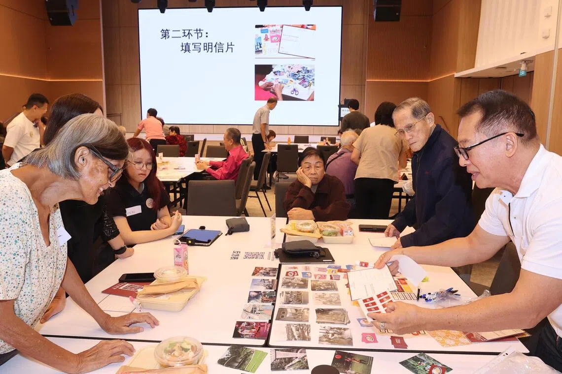 80岁的林照炎（右二，黑衣长者）与妻子一同出席活动填写故事卡，他对五六十年代频发的水患记忆犹新。正因为经历过当年的动荡与不便，林照炎深感今日新加坡的成果来之不易。（邬福梁摄）