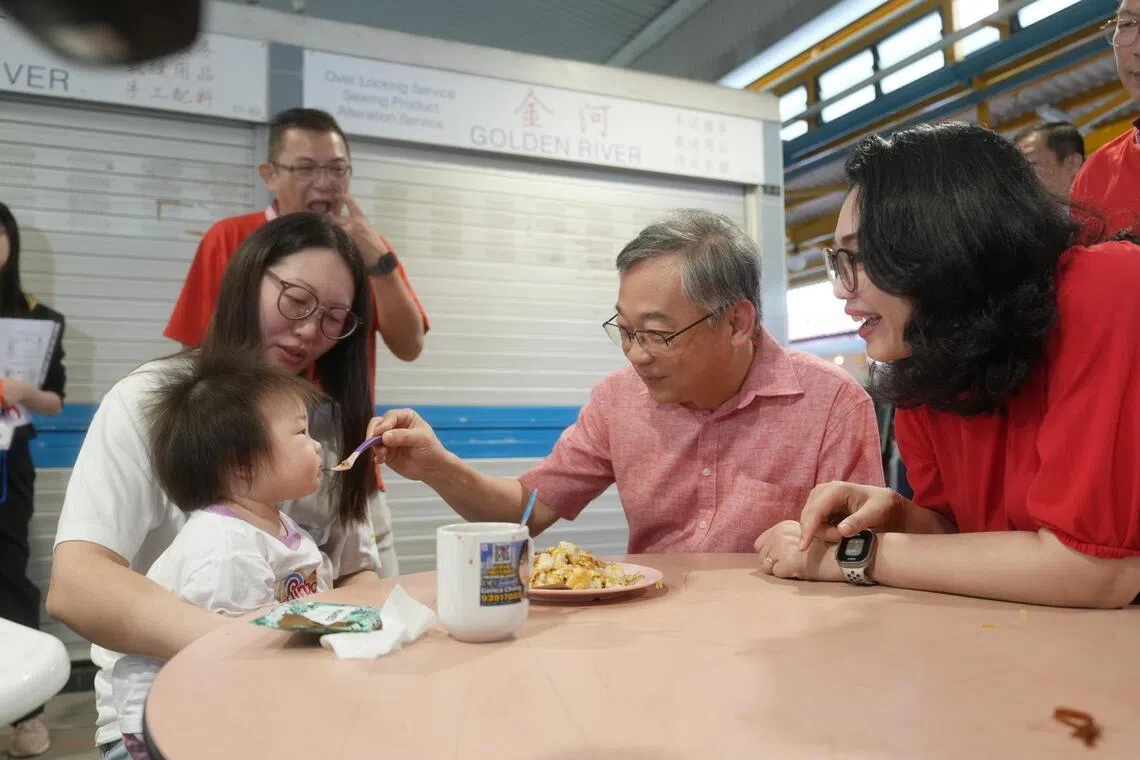 副总理兼贸工部长颜金勇（右二）星期天走访凤山小贩中心与居民交流时，还特别举起汤匙给一名女童喂食。右一为负责凤山区事务的东海岸集选区议员何礼娜。（谢智扬摄）