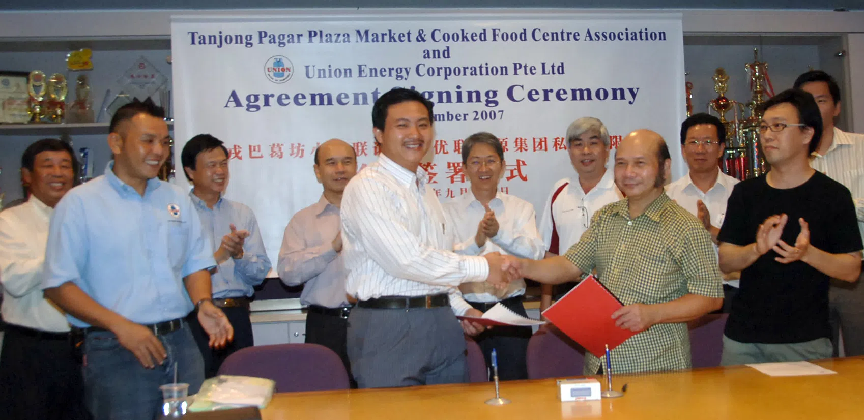 张学彬（前排左二）推动优联竞逐熟食中心煤气供应市场，包括成功取得丹戎巴葛坊小贩联谊会签署煤气供应项目；父亲张建安（后排左二）当时见证签约仪式。这项突破也成为优联扩大市场的重要里程碑。（档案照片）