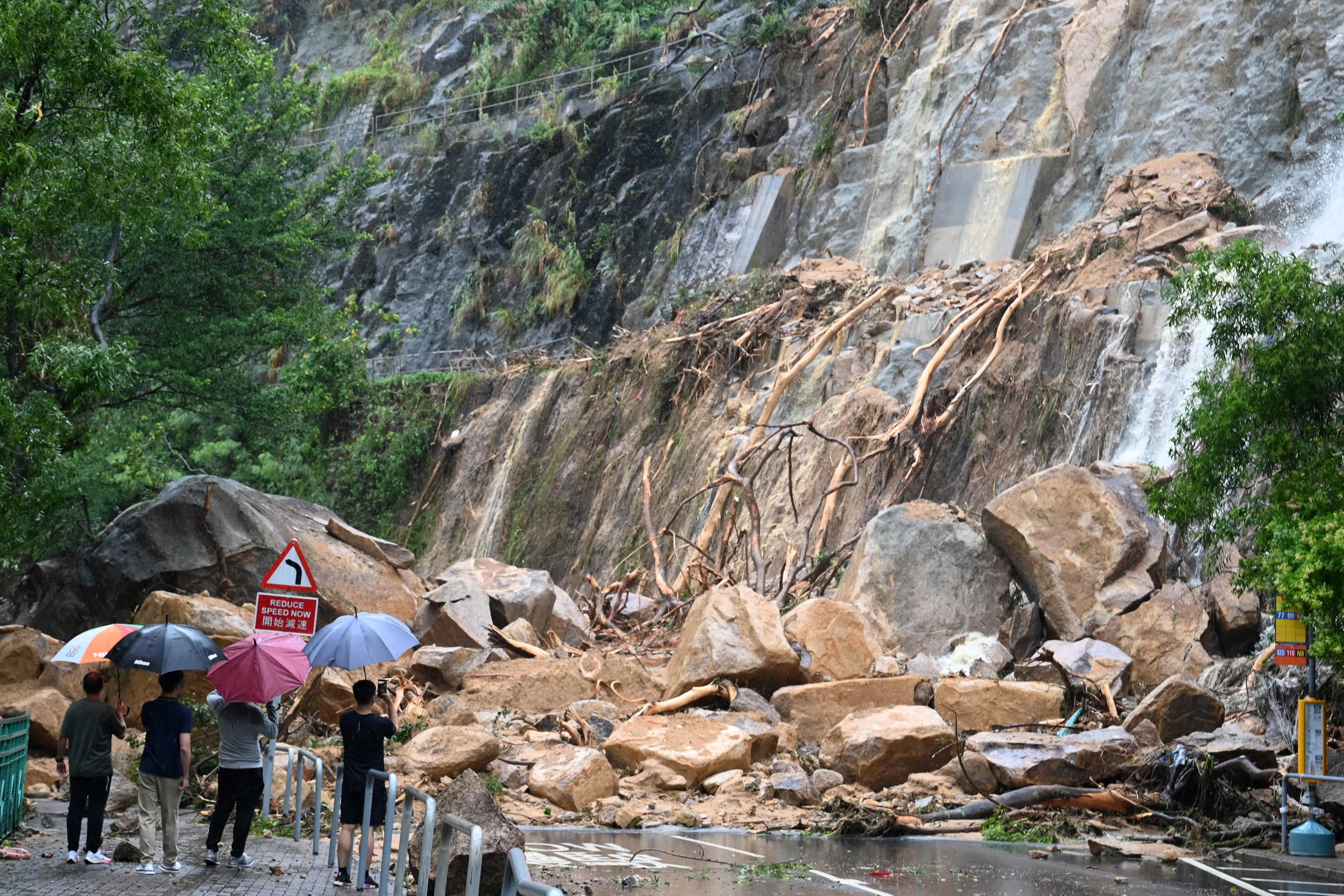 持续暴雨造成港岛东区筲箕湾耀兴道一个地段发生滑坡泥石流，滑落的巨石阻断道路。（法新社）