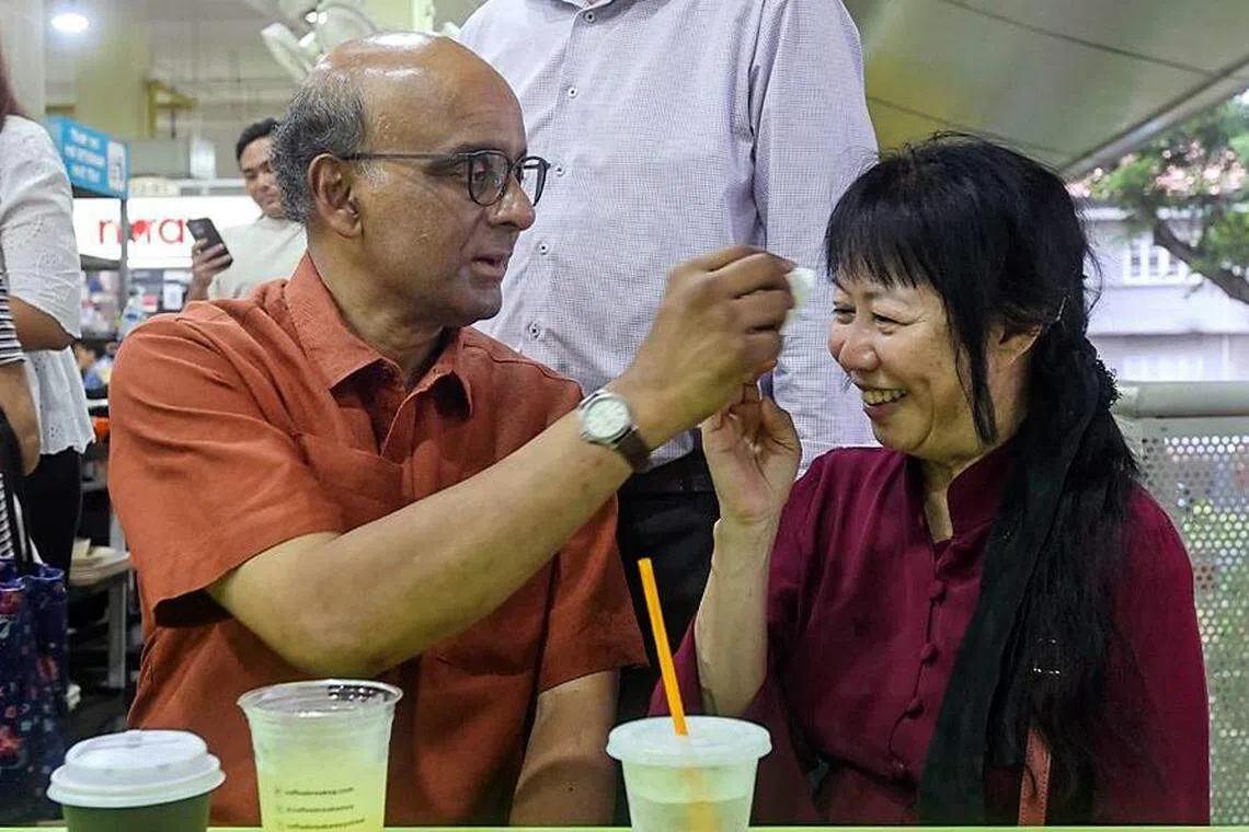 总统候选人尚达曼（左）与夫人珍一藤木8月25日走访厦门街熟食中心时，两人买了饮料短暂休息，尚达曼也贴心为夫人擦汗。（关俊威摄）