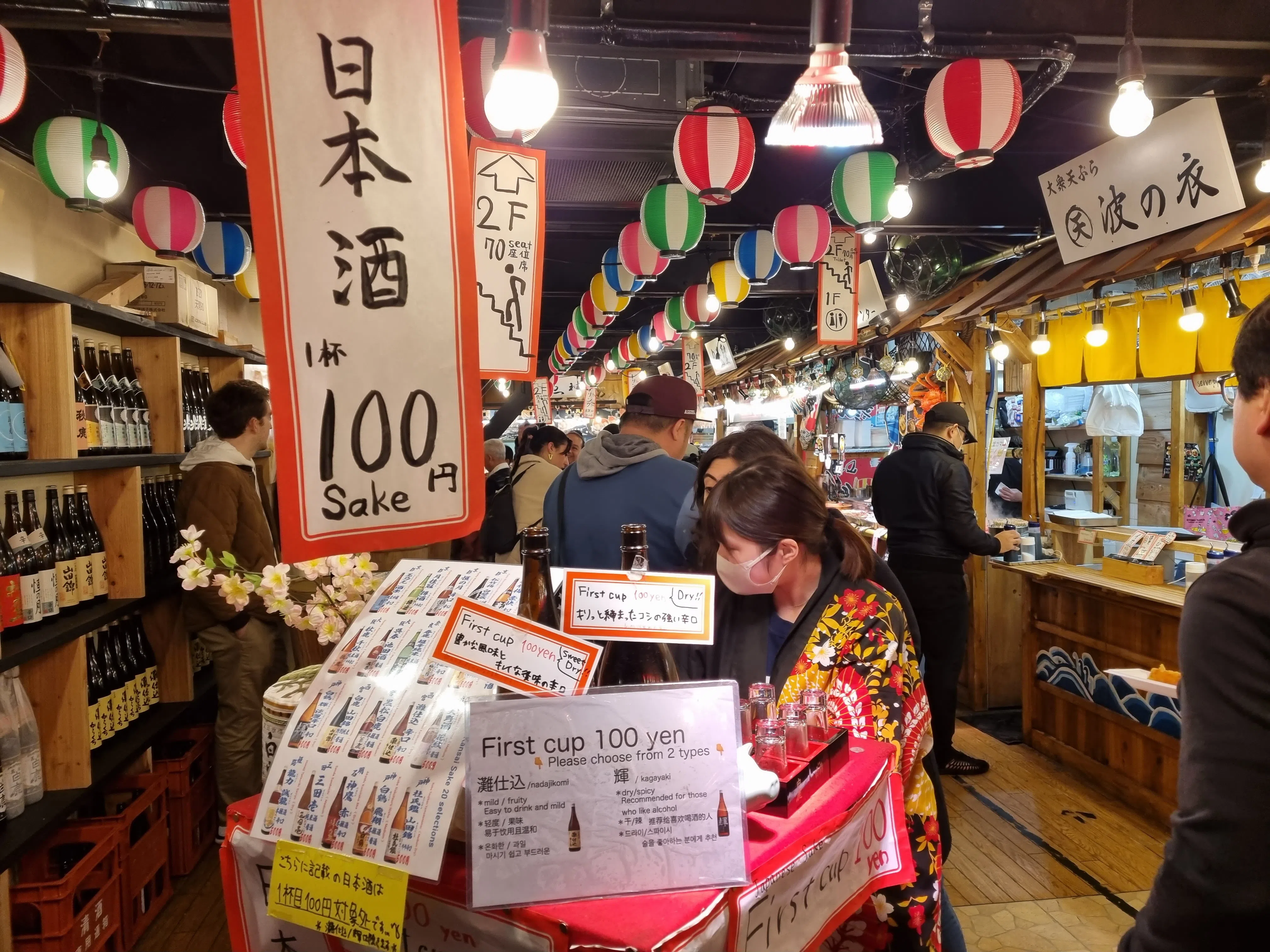 锦市场内有琳琅满目的小吃摊，售卖烤牛肉串、生鱼片和关东煮等，也有100日元的清酒。（廖慧婷摄）