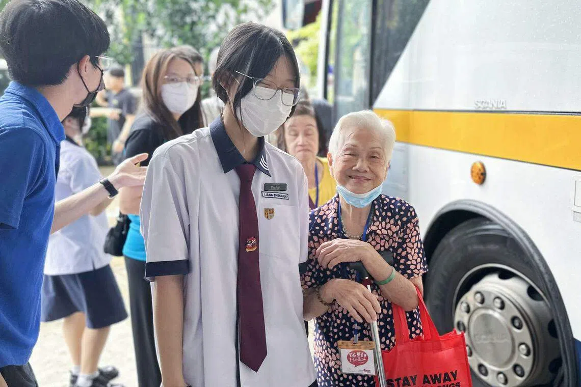 三育中小学教师（蓝衣）和学生（中），接待参与“让爱传出去”中秋节园游会的年长者。（三育中小学提供）