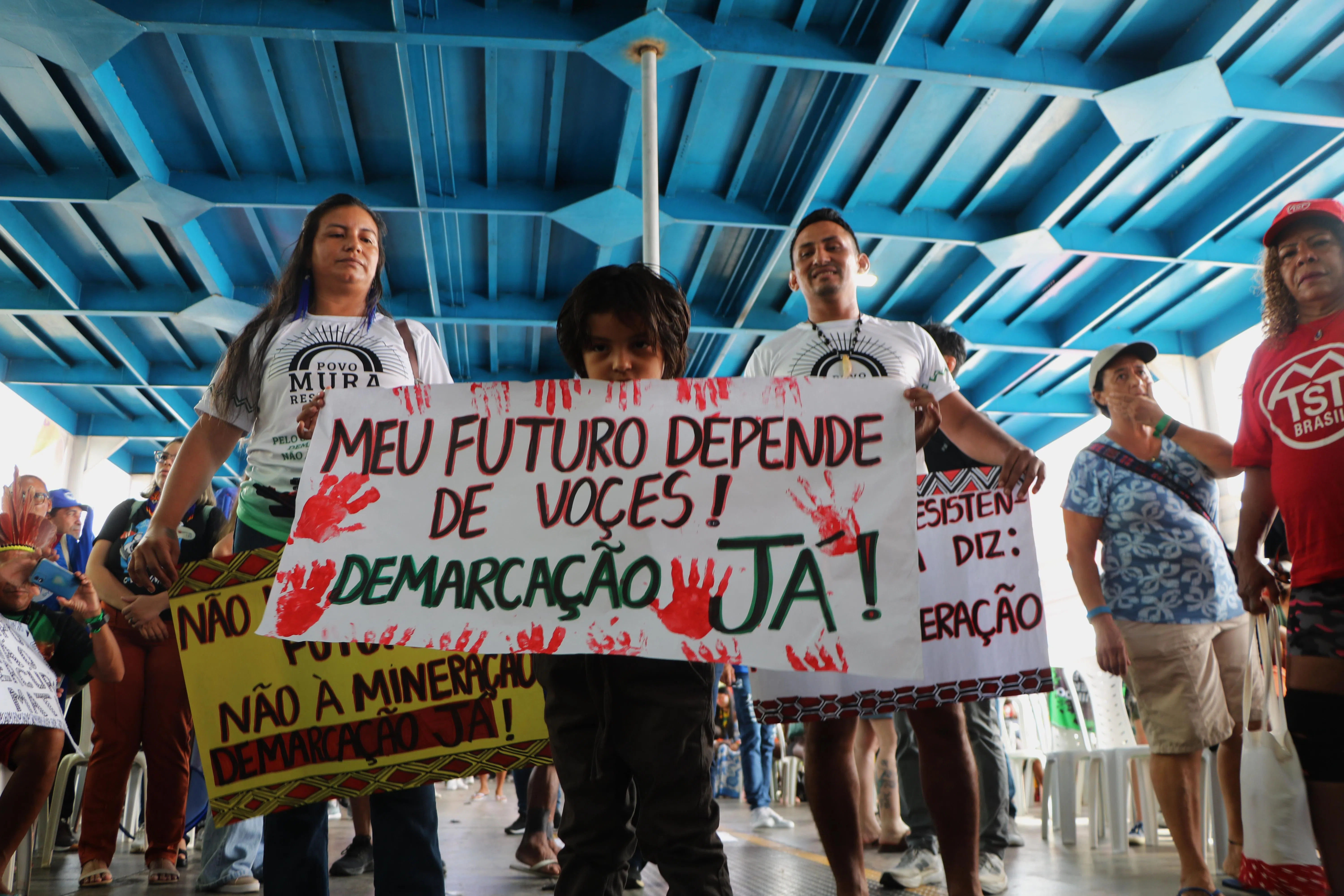 家长带着小孩前来集会，图中孩子拿的告示牌写着：我的未来取决于你，现在就划界（意即：请勿占用原住民的土地）！（蔡玮谦摄）