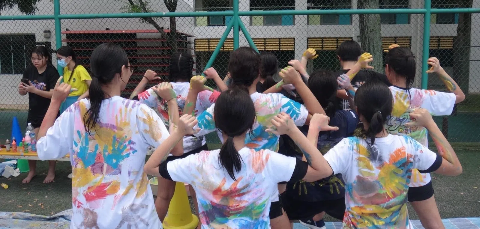 水上嘉年华设计衣服摊位。学生们把前臂涂上油漆，然后拥抱朋友，把手臂的图案印在衣服上。（黄思瑞摄）