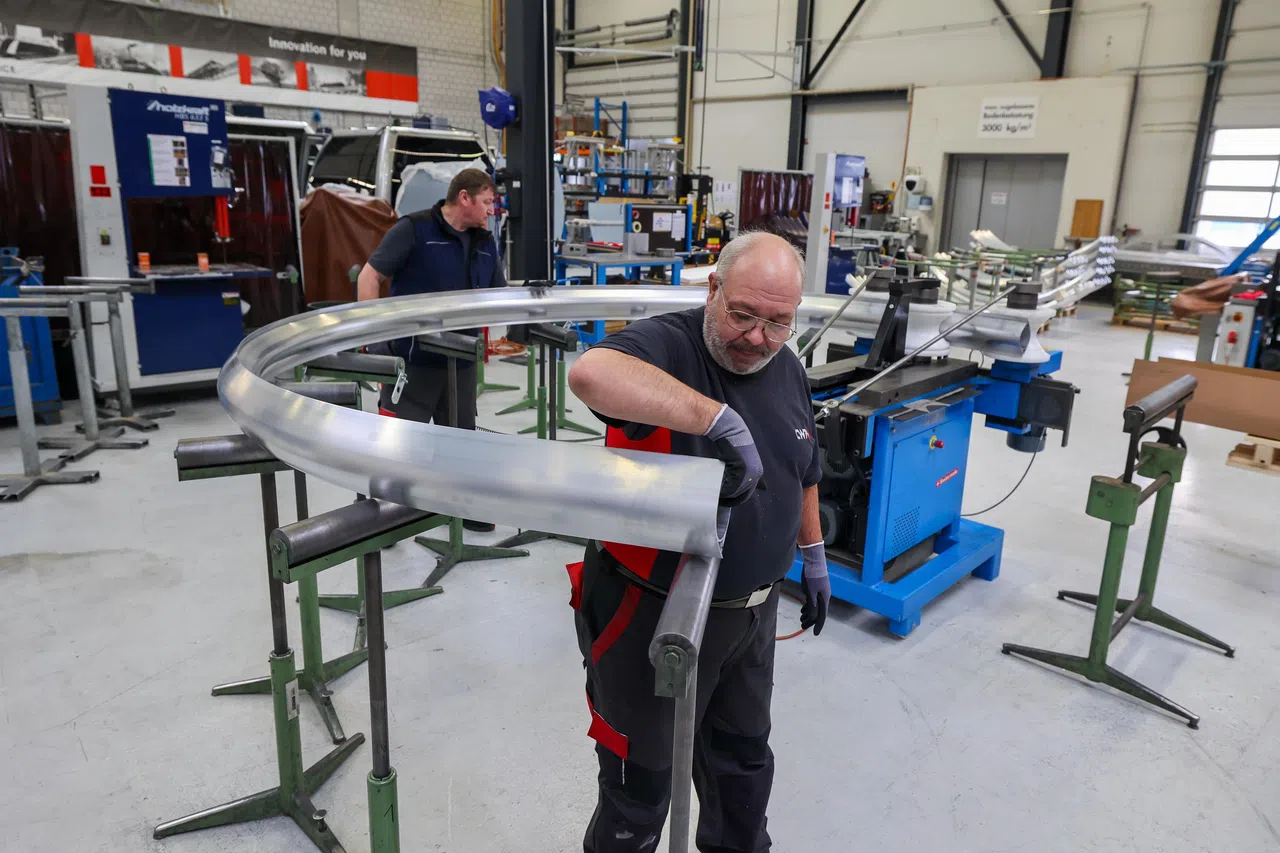 银灰色的圆形缆车主体由铝制成，图为两名CWA技工奥利弗（Oliver Zivkovic，左）及帕斯卡（Pascal Rodriguez，右）使用机器，切割弯曲的铝制品，准备当成缆车主体的支柱。（卓祾祎摄）