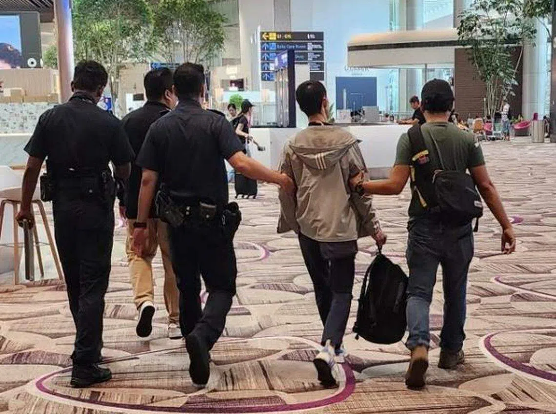 被告（右二）在樟宜机场离境大厅被警方拦下，押回警局。（警方提供）