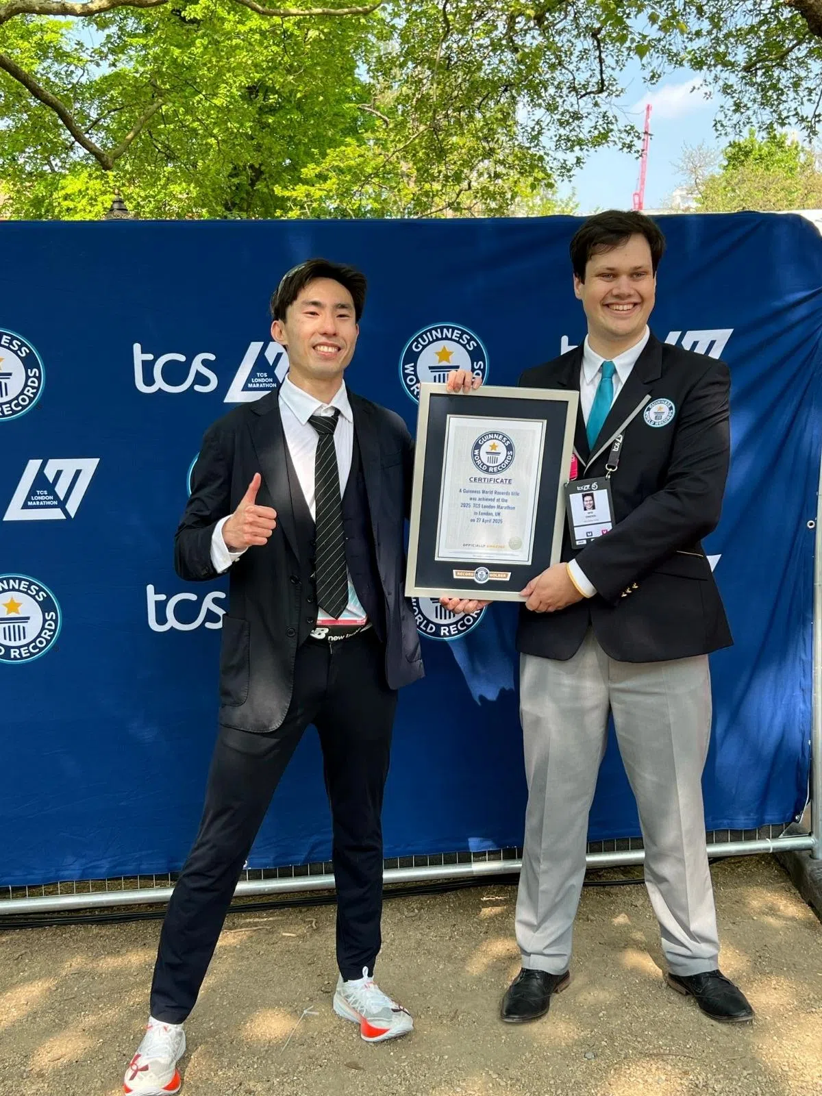 苏睿勇（左）在刷新纪录后，身着参赛的西装和健力士证书合影留念。（取自健力士世界纪录X平台）