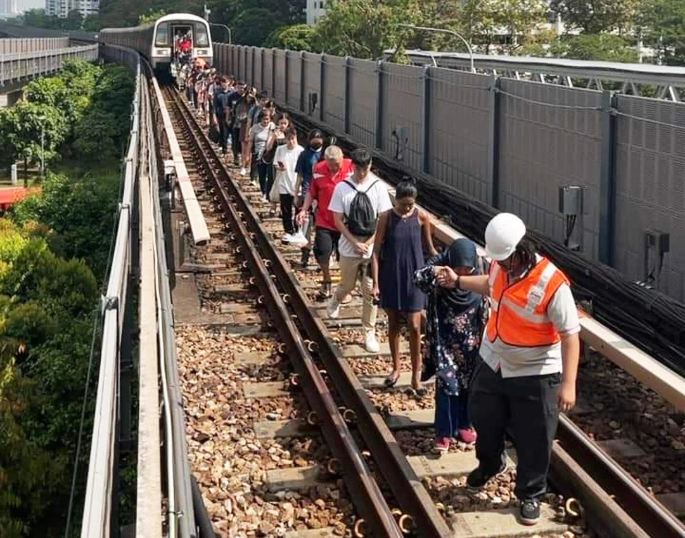 约850名受列车故障影响的乘客随着地铁站人员的指示，沿轨道走回金文泰地铁站。（取自SMRT脸书）