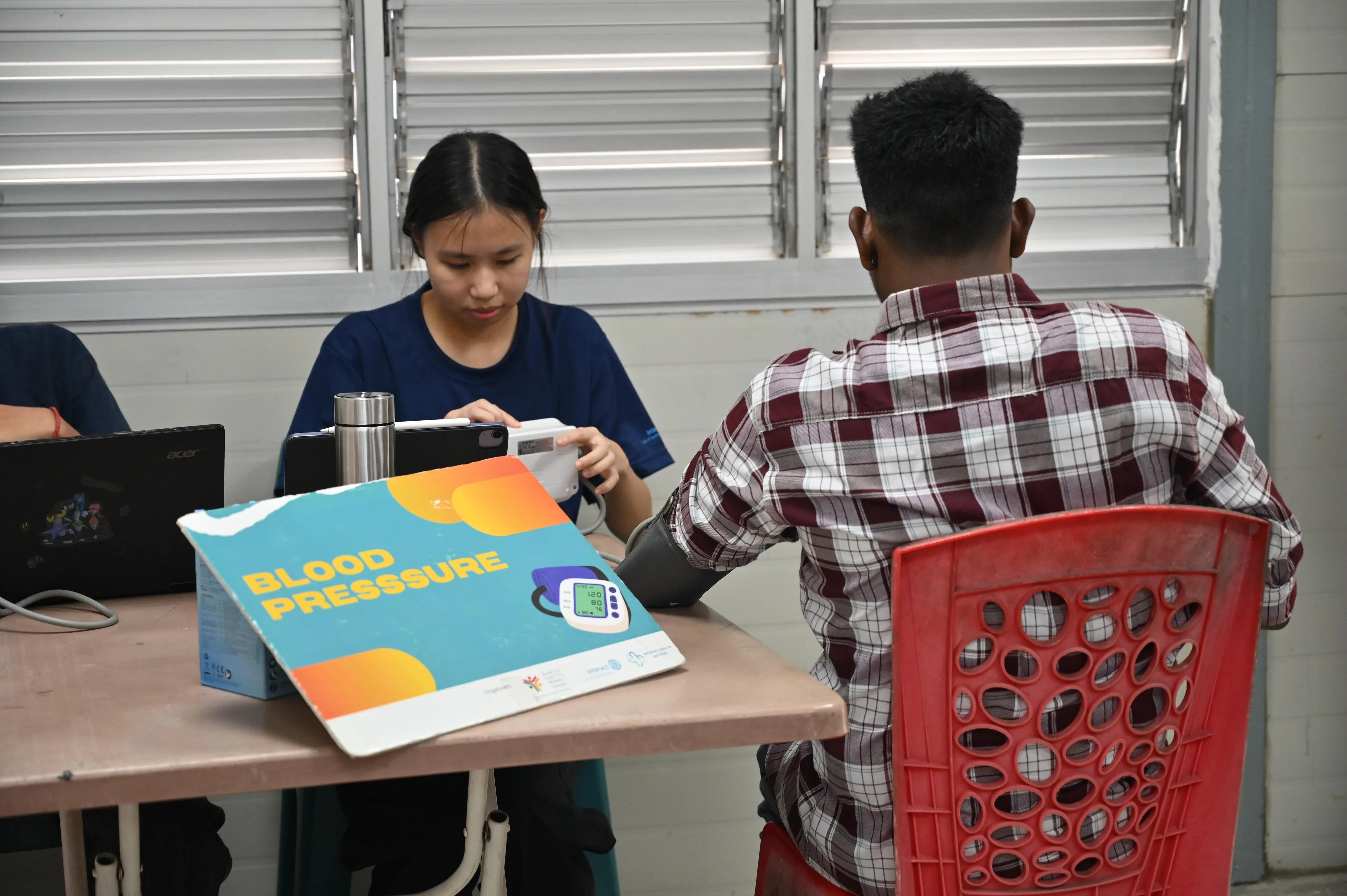 “客工健康关怀”的学生义工在免费体检活动中，为客工测量血压。（受访者提供）
