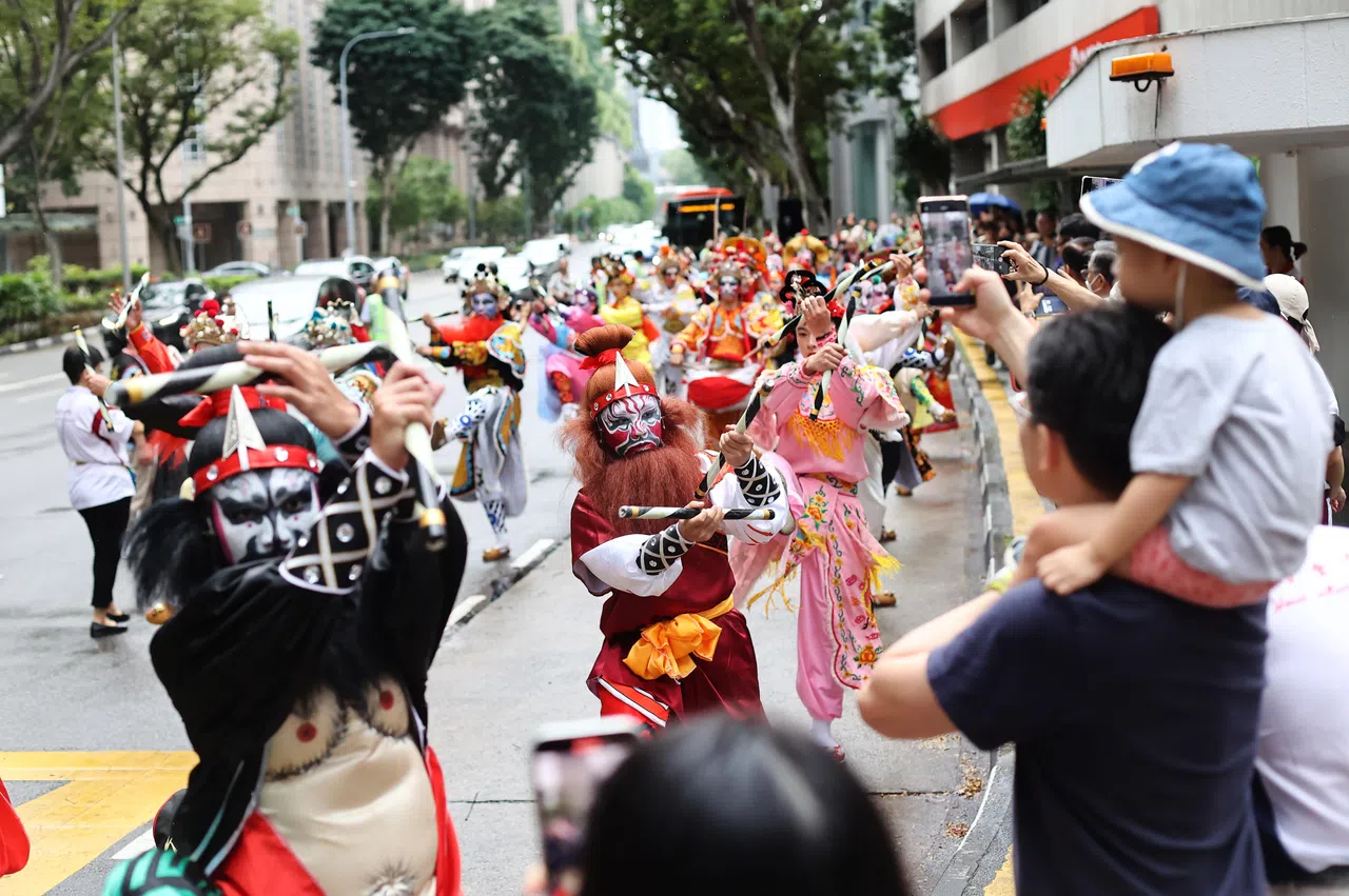 潮汕英歌舞、潮州大锣鼓、喜庆锦旗等列队在粤海清庙附近游行，吸引许多公众围观。（陈渊庄摄）