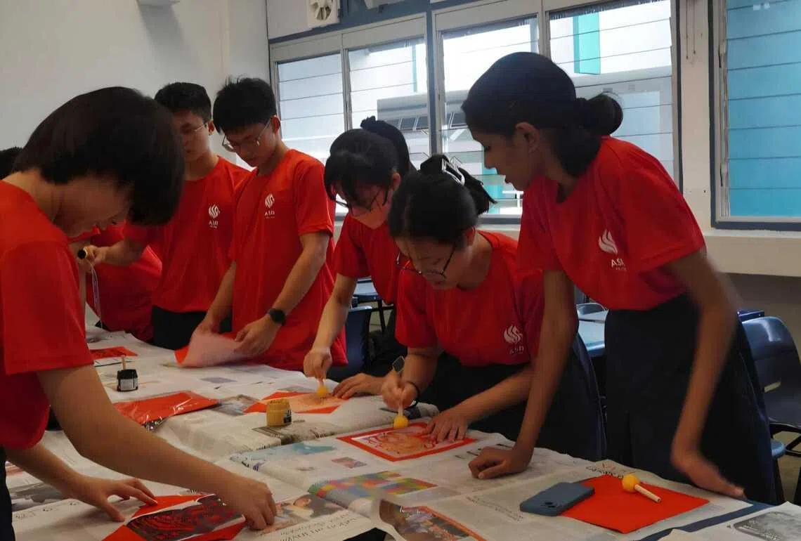 各班学生围在桌前，利用海绵拓印和校方提供的书法模板、红纸创作。（安德逊实龙岗初院提供）