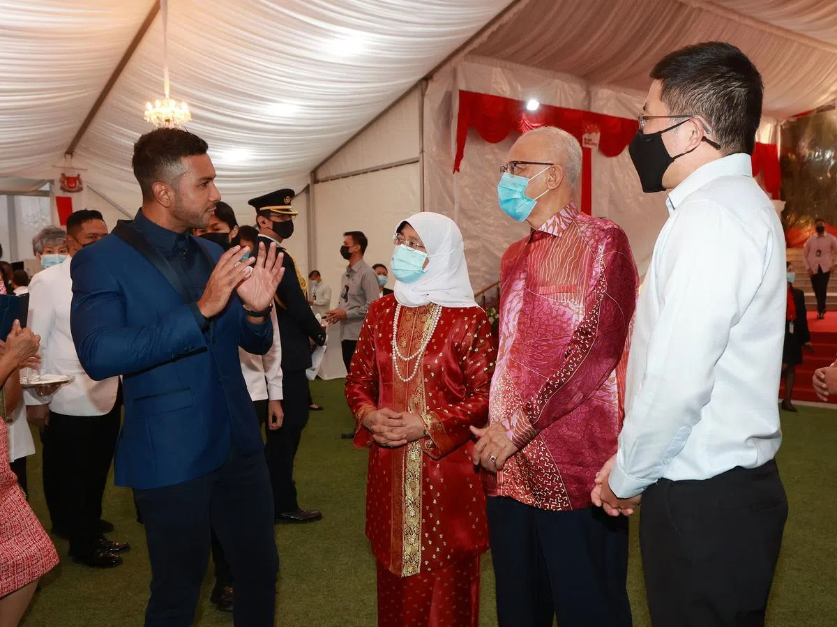 哈莉玛总统（左二）与夫婿穆罕默德（右二）在本地歌手陶菲克（Taufik Batisah，左一）为酒会献唱今年国庆主题曲《携手同心向未来》后，与他交流。（唐家鸿摄）
