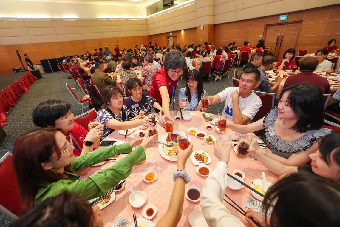 《联合早报》星期天在报业中心礼堂举行早报专栏作者午餐交流会，约140人应邀出席。图为新报业媒体华文媒体集团社长李慧玲（红衣站立者）向一桌与会者敬茶。（白艳琳摄）