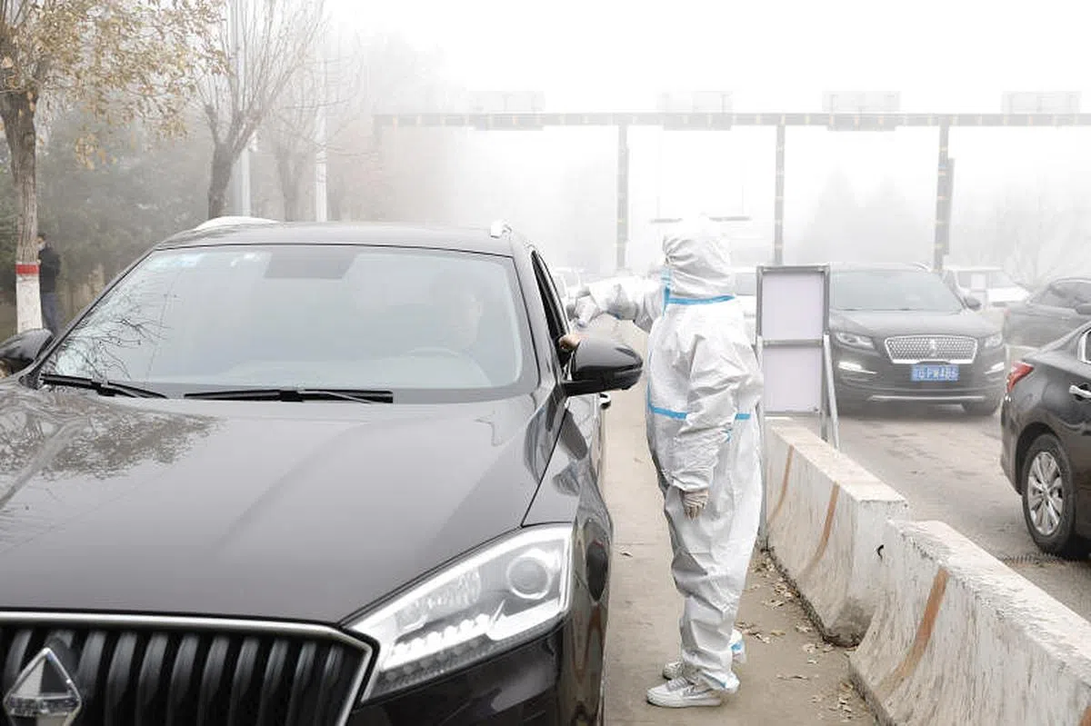 11月17日，河北省廊坊市大厂回族自治县谭台治安检查站工作人员对进京人员进行测温检查。（中新社）