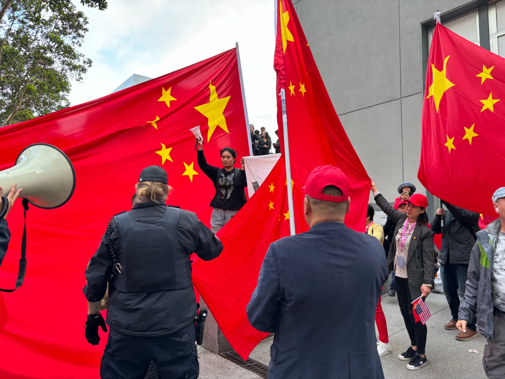 一名示威者举横幅抗议，周围的群众用大幅中国国旗试图将她的诉求遮挡起来。（韩咏红摄）