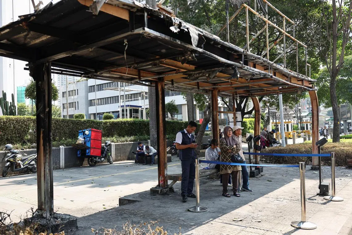 雅加达局势星期二（9月2日）总体维持平静，民众在遭示威者纵火局部烧毁的巴士站等候巴士。（路透社）