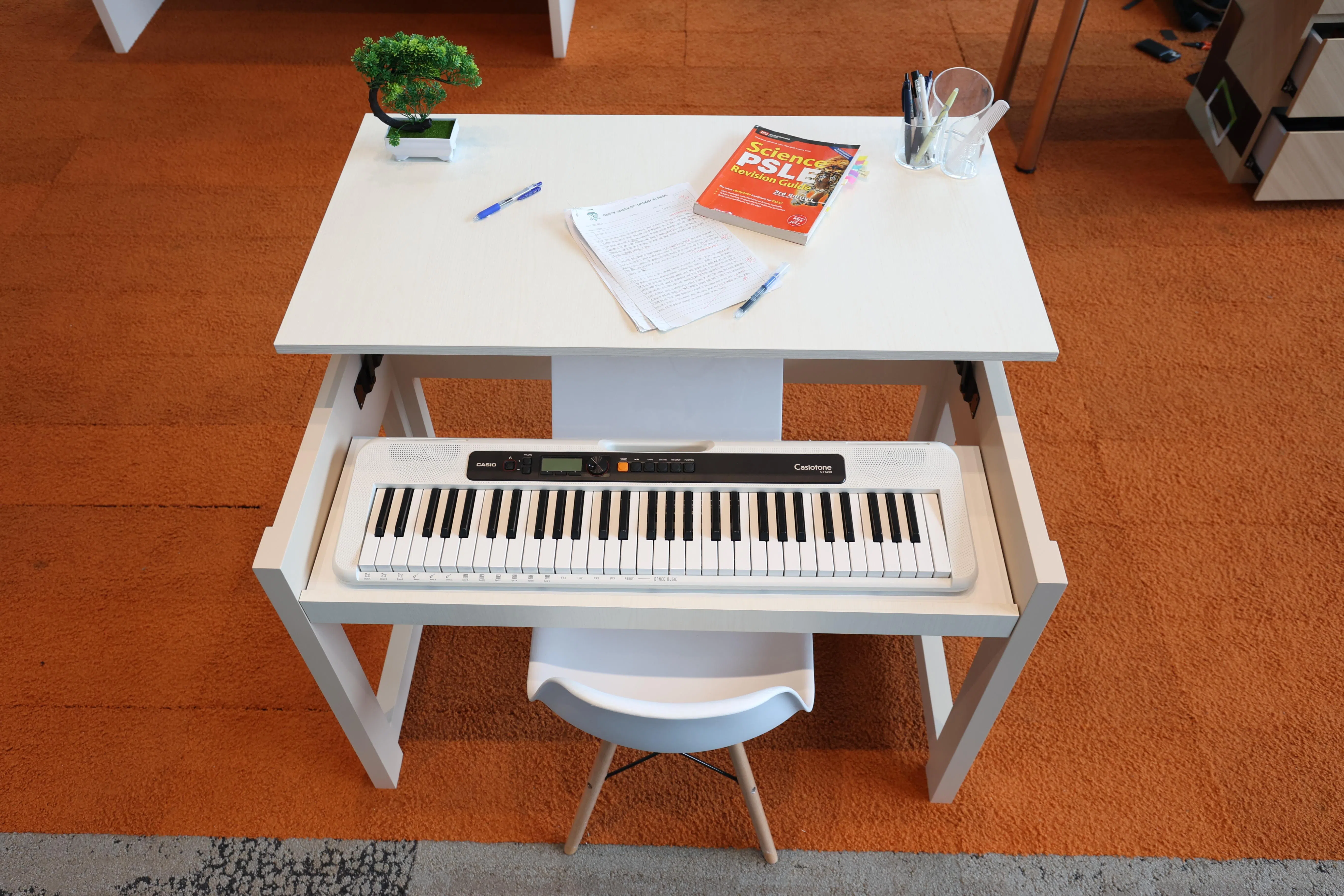 “弦桌”暗藏玄机：桌面抬起来，下面就是电子琴。（何家俊摄）