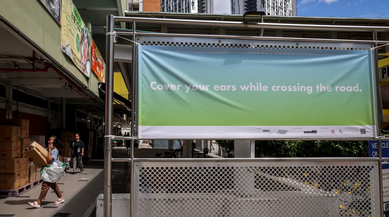 这个靠近丹戎巴葛坊路口的横幅要求人们过马路时捂住耳朵。该公共艺术项目的横幅和指示遍布丹戎巴葛地区13个地点，包括武吉巴梳路、艾弗顿园、达士敦路和岌巴路。（叶振忠摄）