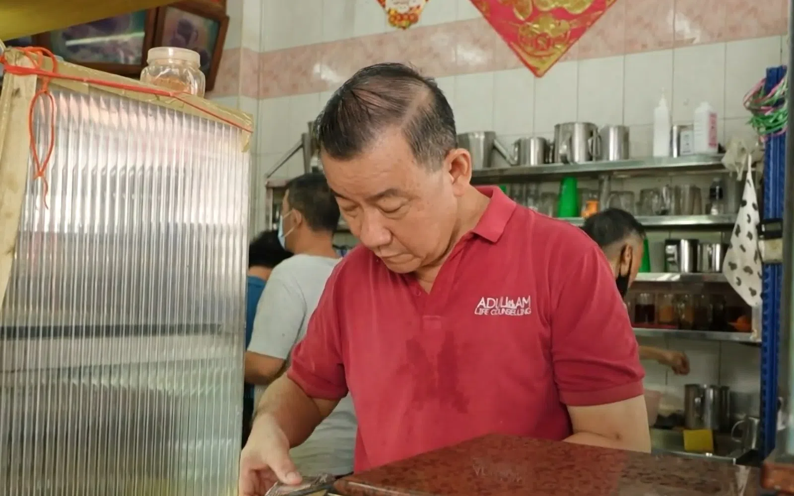 王其俊在咖啡店里忙前忙后，衣服透着汗水。（视频截图）