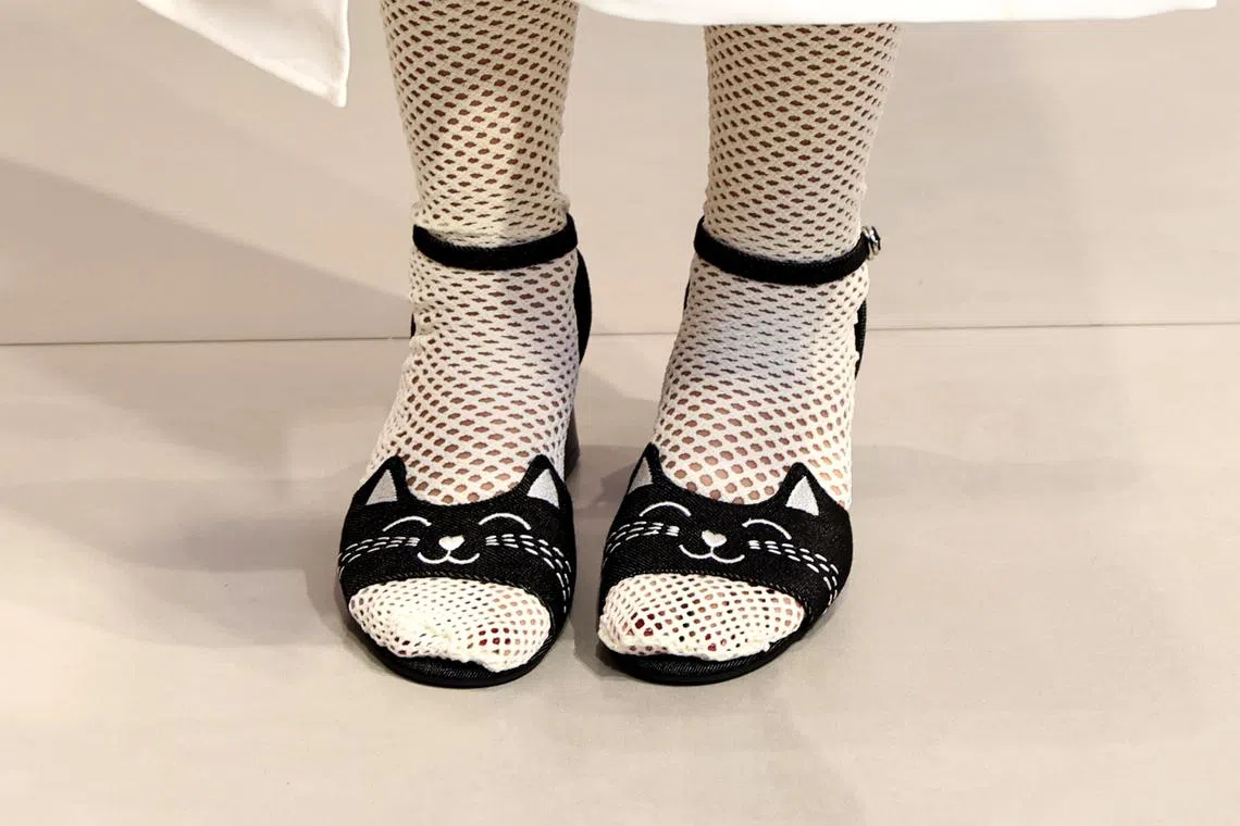 白薇秀穿上融入猫脸图案设计的鞋子出席活动，她说自己和女儿都爱猫。（龙国雄摄）