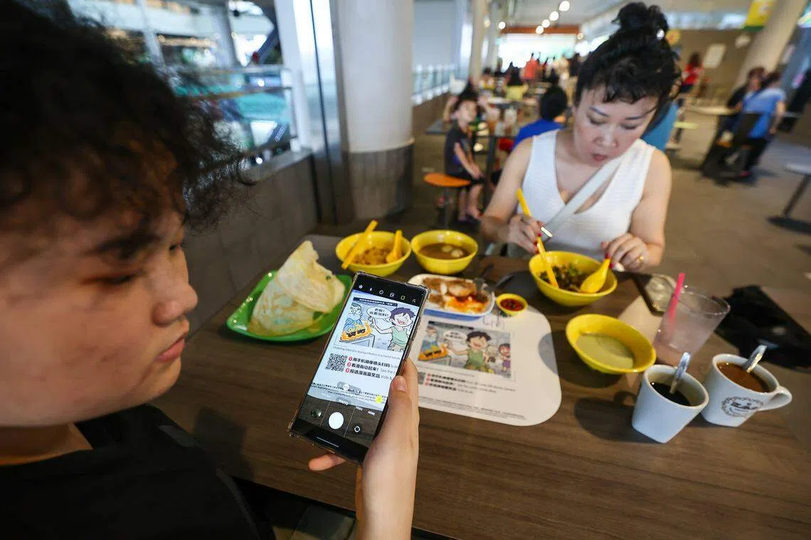 公众可在十间邻里小贩中心的桌子上看到这些漫画作品，通过扫码参与互动看漫画“动”起来，还有机会赢取奖品。（陈渊庄摄）