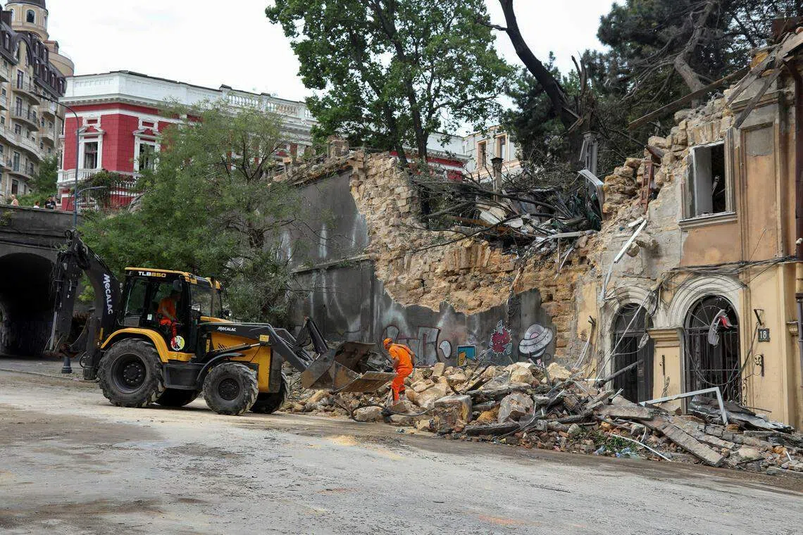 23日，敖德萨市政工人正在一座受损建筑旁清理瓦砾。（路透社）