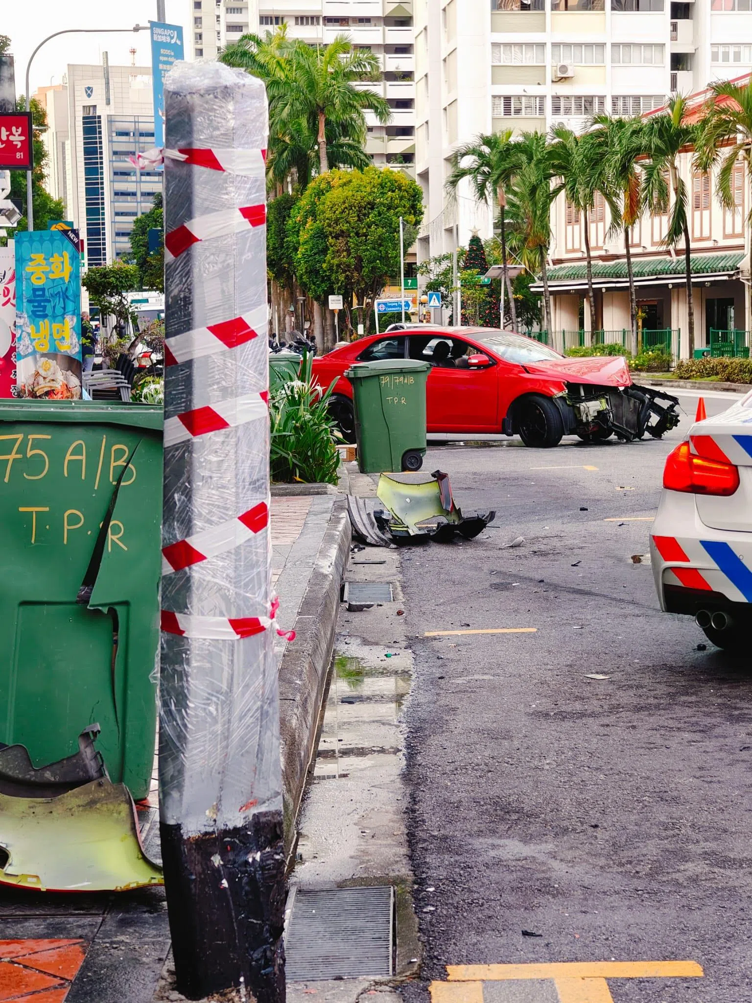 灯柱被撞至严重变形，汽车车头的保险杠掉落在灯柱附近，车头严重撞毁、引擎外露，驾驶座的安全气囊也弹出。（受访者提供）