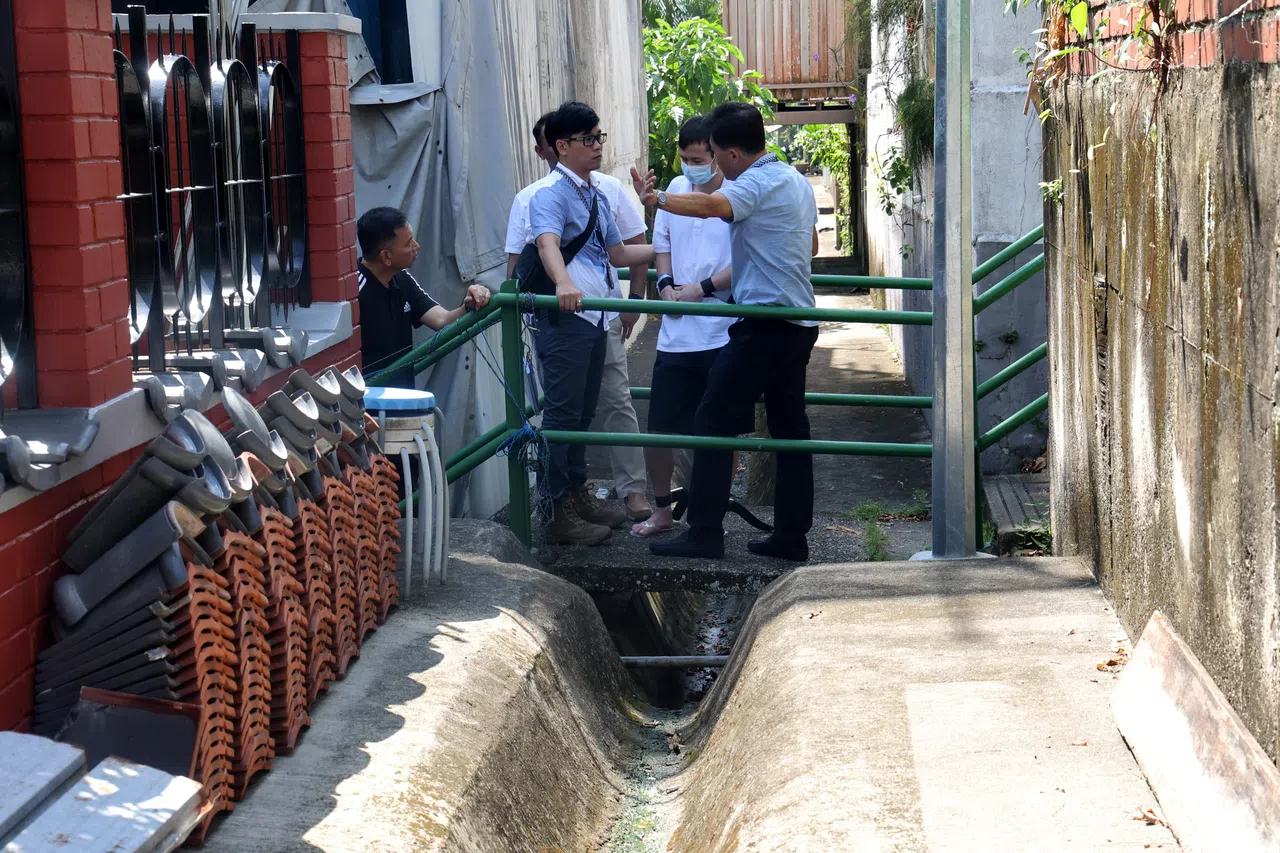 被告（白衣者）被押至私宅小径处，跟在场警员叙述翻越沟渠闯入私宅单位的干案路线。（邬福梁摄）