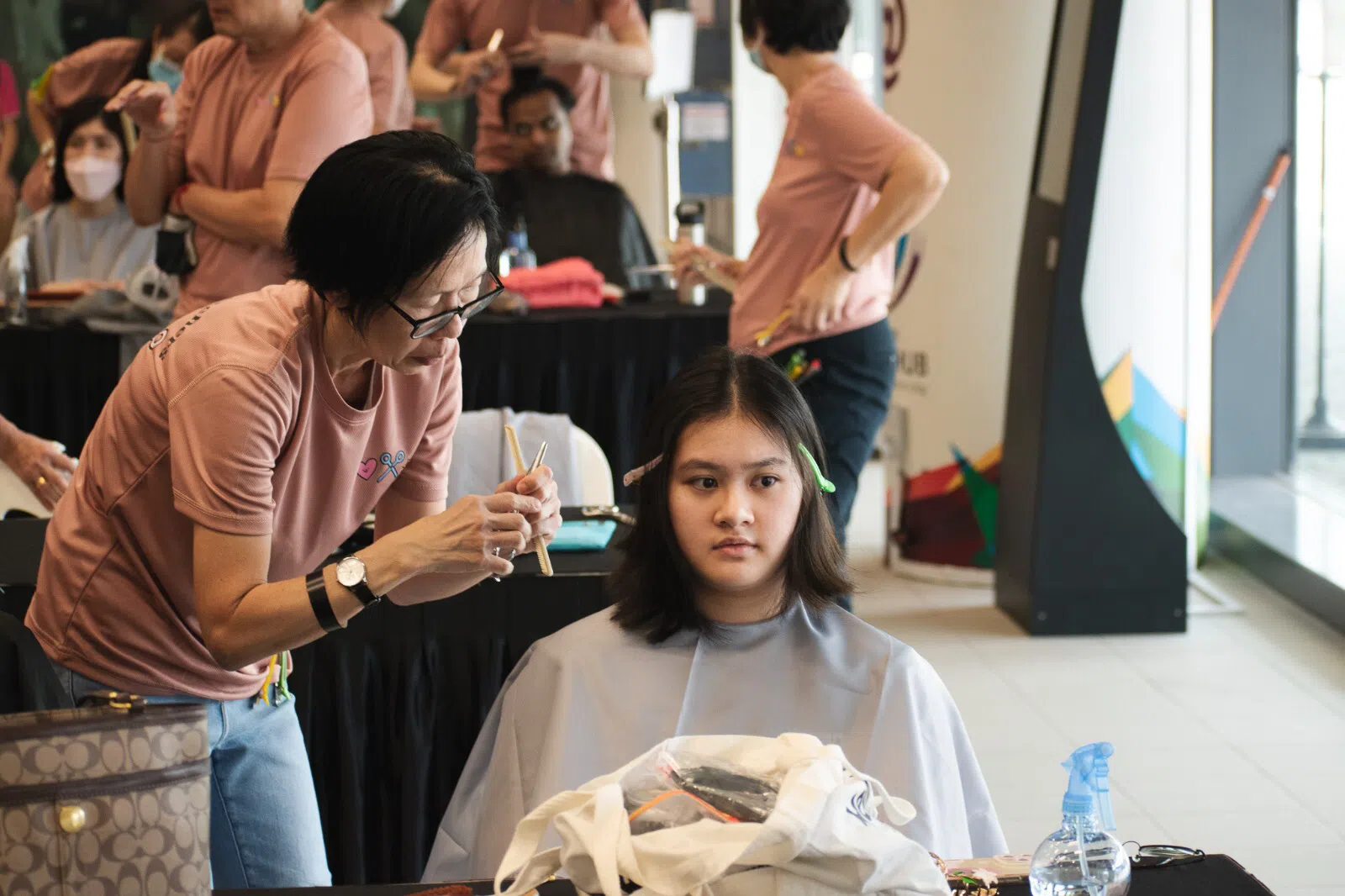  美发师在后台动作娴熟地为捐发者修饰发型。（林恩摄）