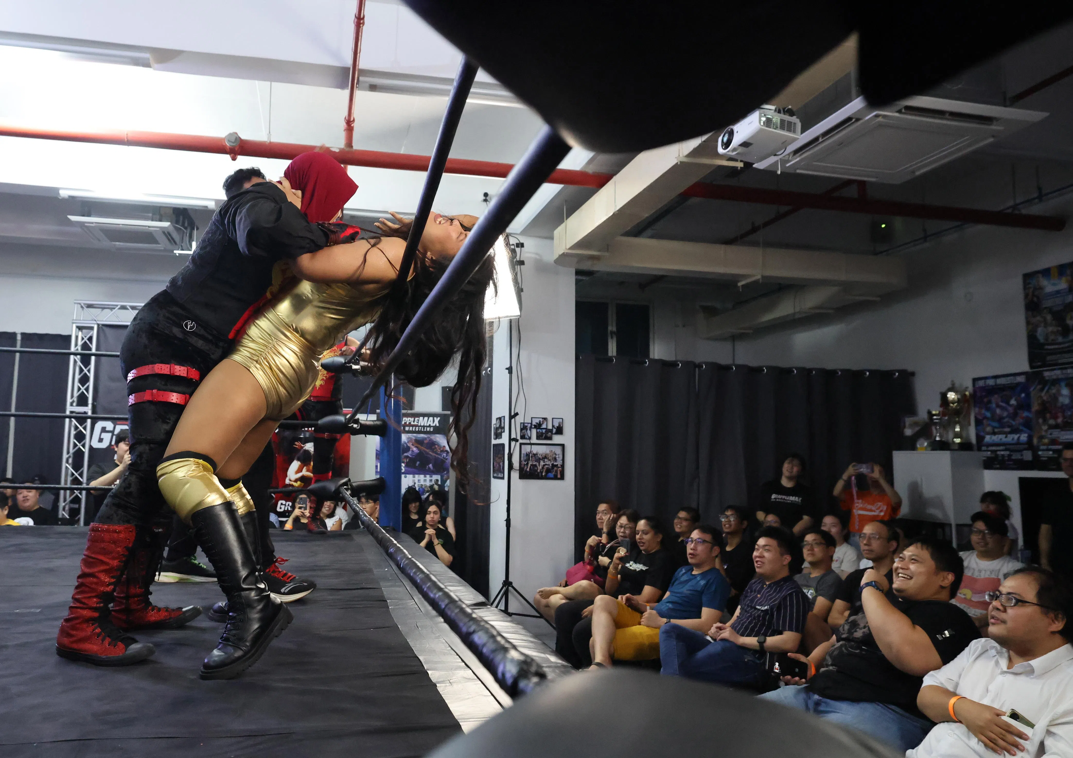 Divya正在被另一名马来裔女摔角员压制，台下观众紧张期待。（梁麒麟摄）