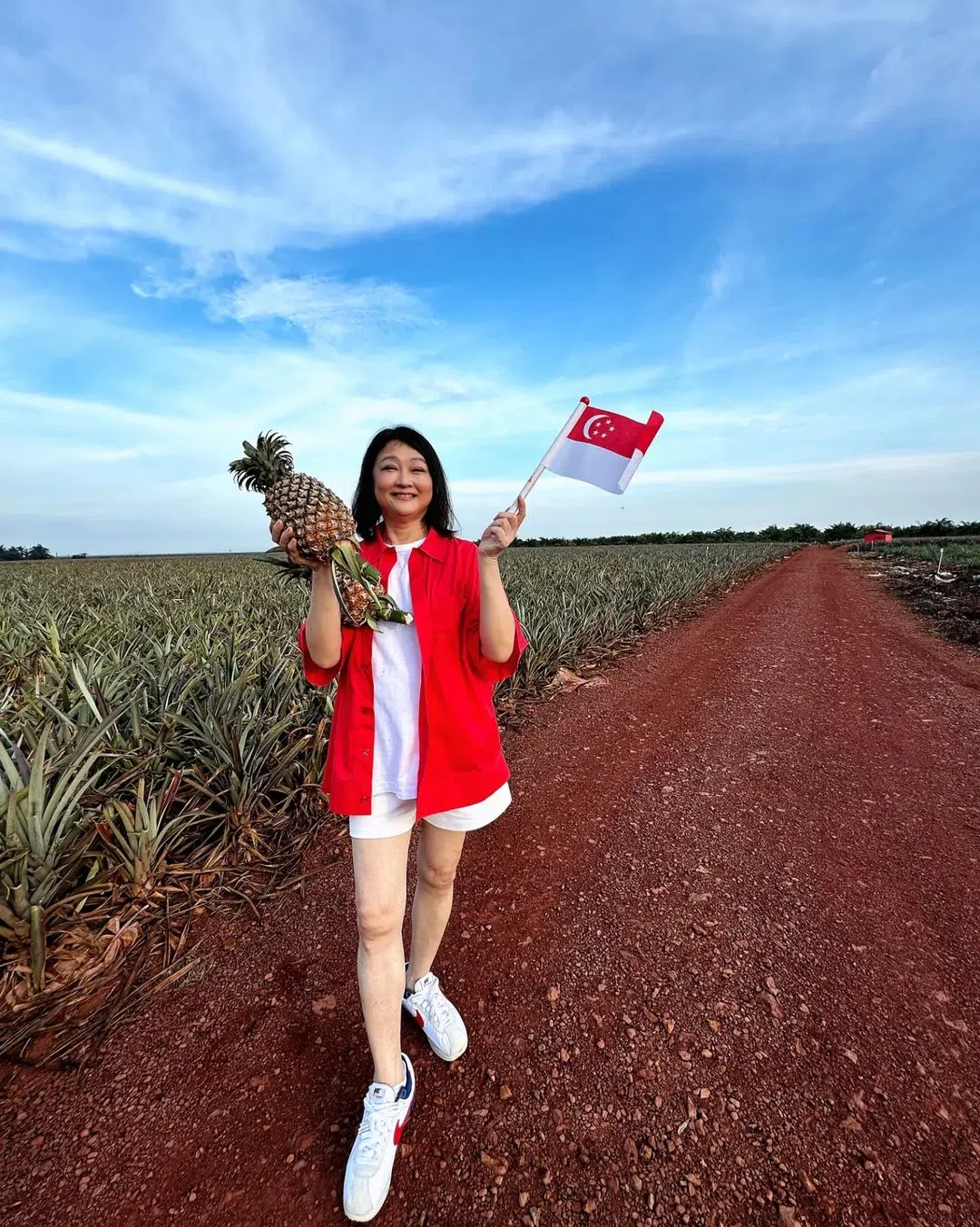 陈莉萍一手挥着国旗，一手拿着黄梨，加上她的红色上衣，照片很有喜气氛围。（取自陈莉萍IG）