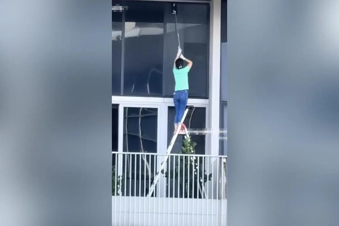女子踩着梯子擦玻璃。（取自网络）