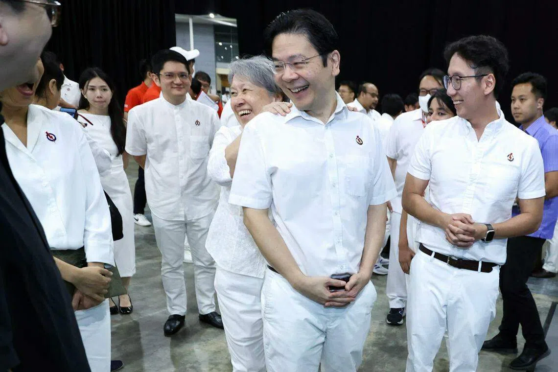 行动党副秘书长、副总理兼财政部长黄循财（中）在行动党大会场边参观“李光耀一百年”展览的时候，也在场的李显龙总理夫人何晶在他背后对肩膀捏了两下，似乎是为黄循财接下来要肩负更重的担子打气。（梁麒麟摄）
