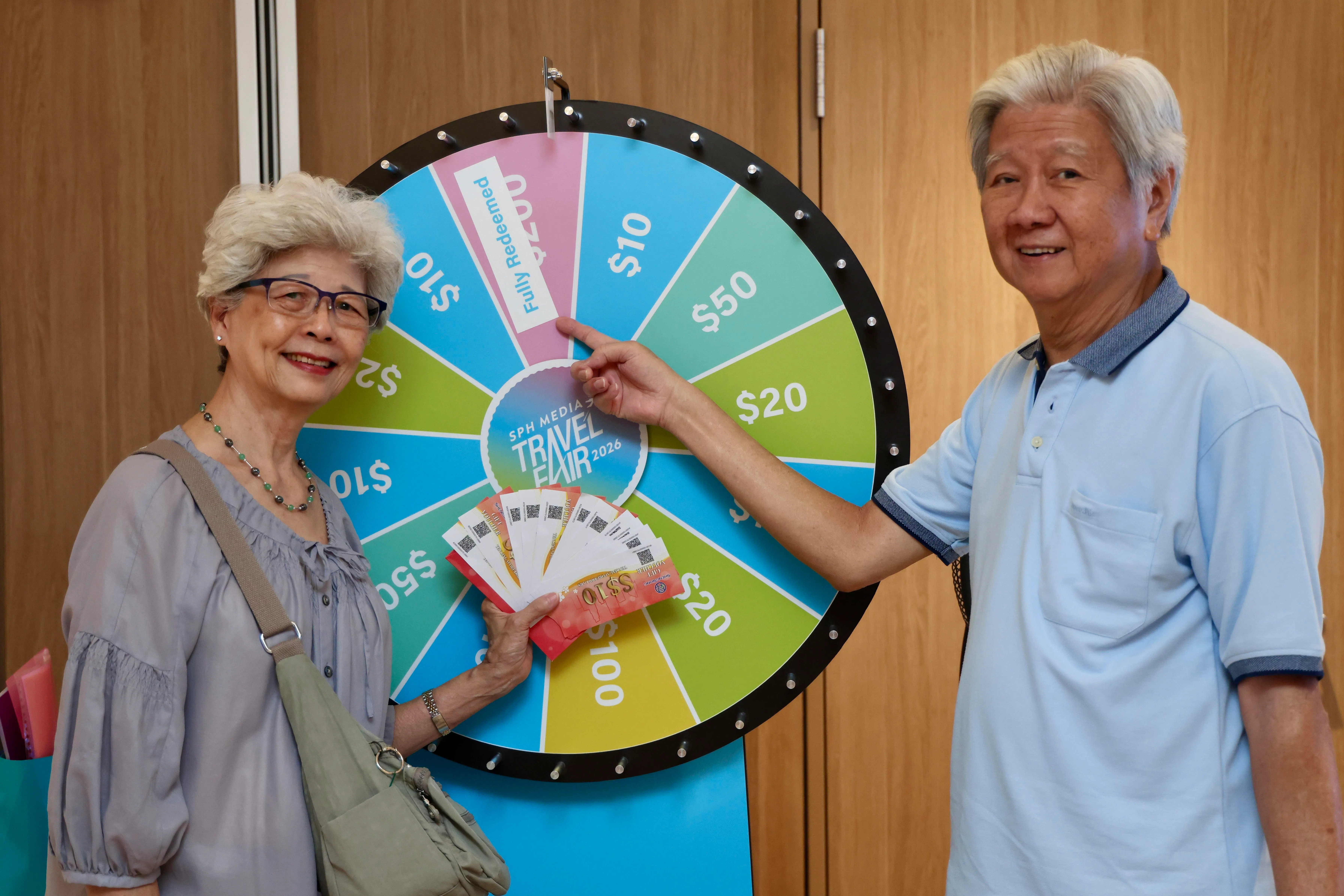 这对参与转轮盘活动的夫妇，赢得了200元现金礼券，可用于任何参展旅行社的配套。（陈斌勤摄）