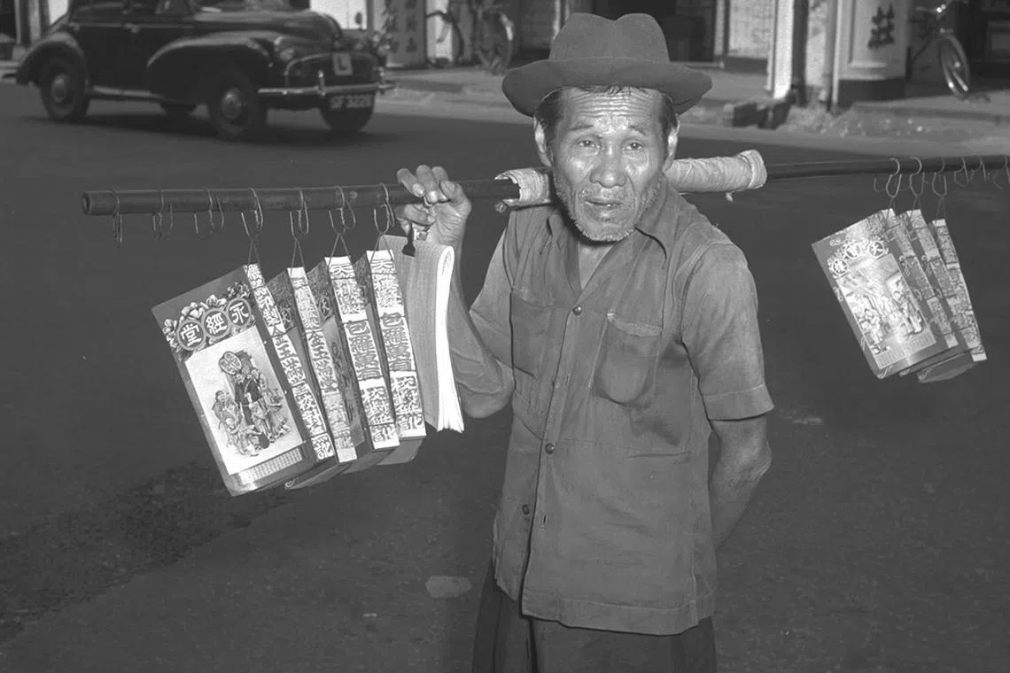他把一年的节气、吉凶、宜忌、冲犯挑在肩上——1955年农历新年在牛车水卖通胜的小贩。（档案照）