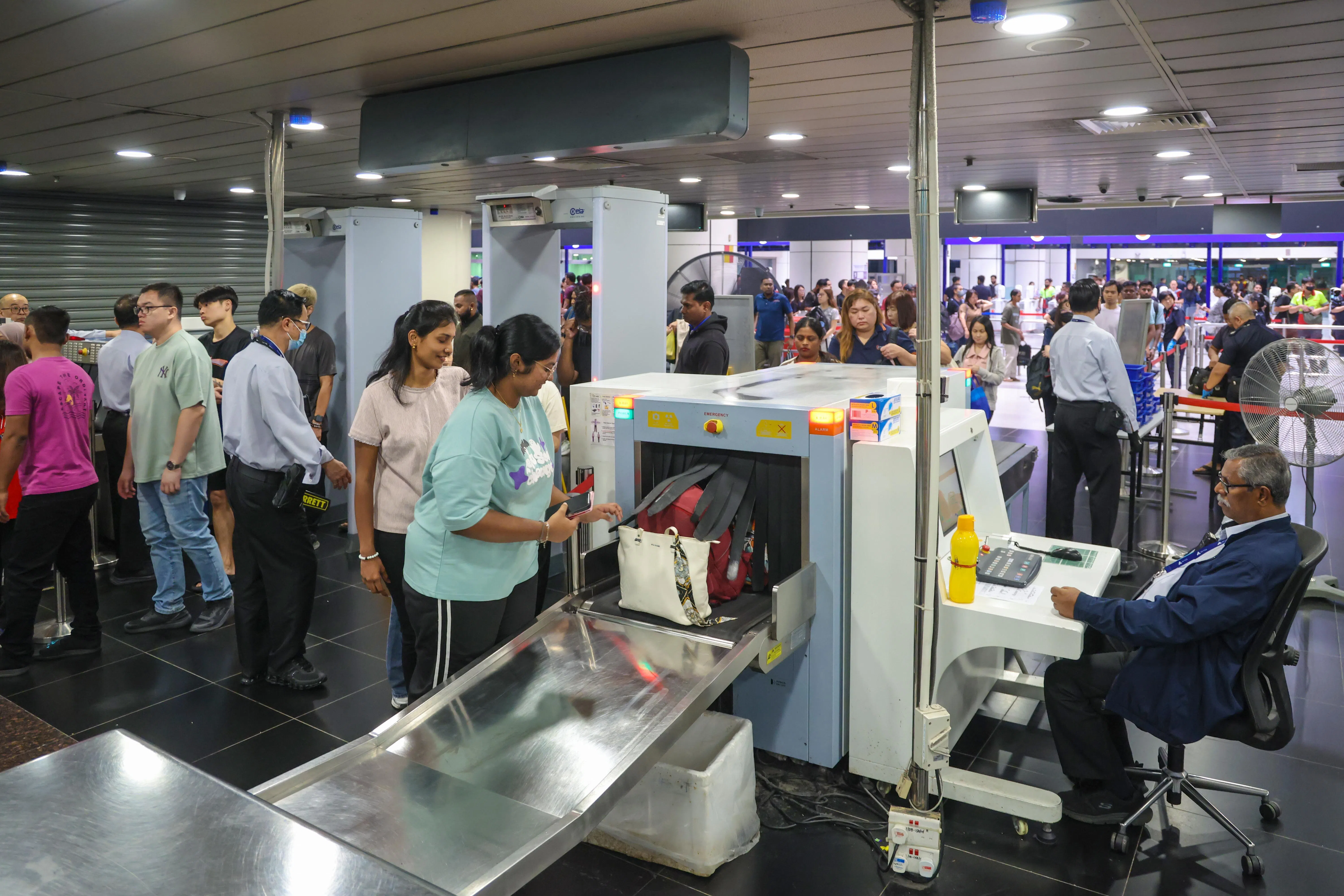 携带背包的旅客都须通过X光安检，执法人员也会筛选出部分携带较大背包的旅客，做更加仔细的翻包检查。（白艳琳摄）