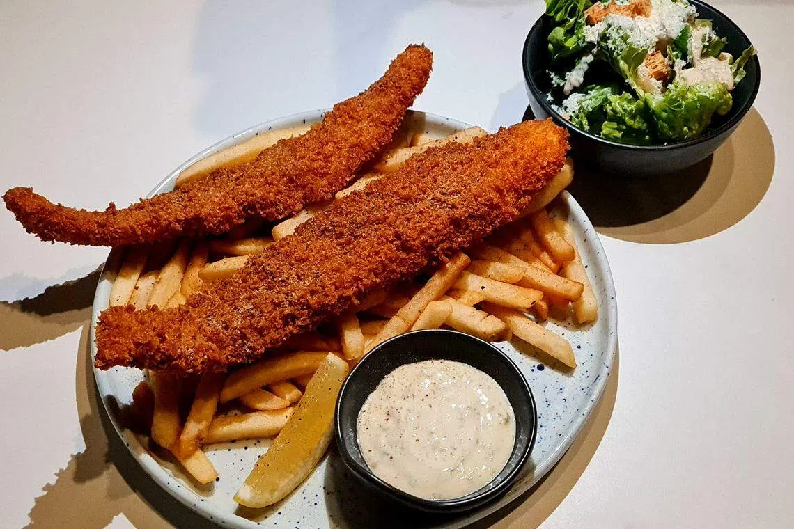 炸鱼薯条伴凯撒沙拉和薯条，吃时搭配餐馆自制塔塔酱，味觉大升级。（叶晓虹摄）