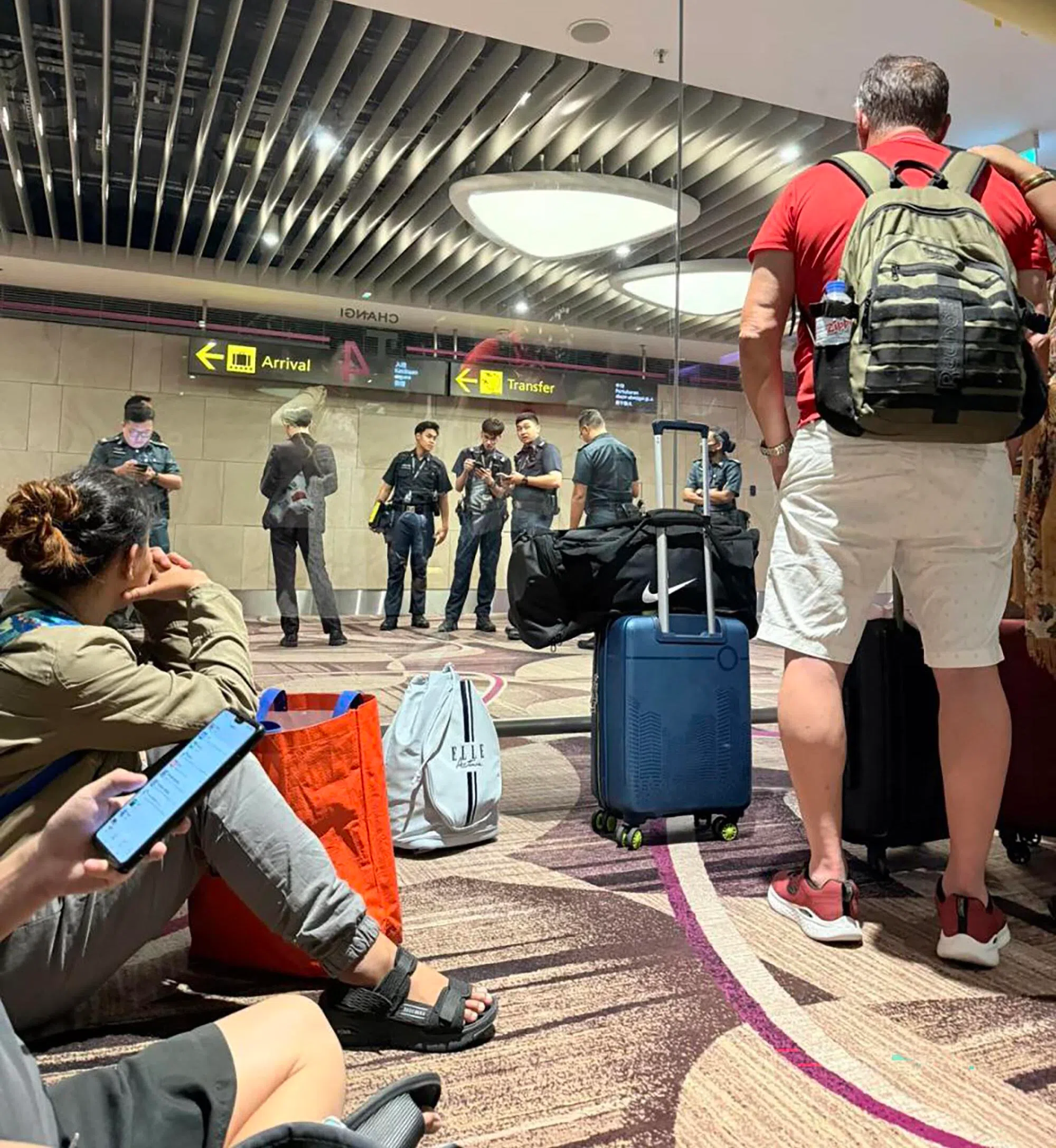 樟宜机场关闭玻璃门后，入境大厅内聚集多名身穿制服的人员，相信在商讨解决方案。（受访者提供）