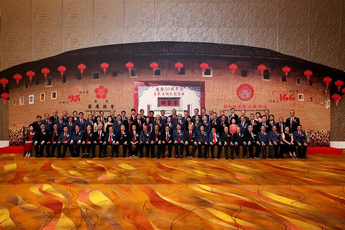 在南洋客属总会95周年和茶阳（大埔）会馆166周年联欢晚宴上，两个会馆的董事与主宾副总理王瑞杰（前排右12）在客家土楼模型前合影。（龙国雄摄）
