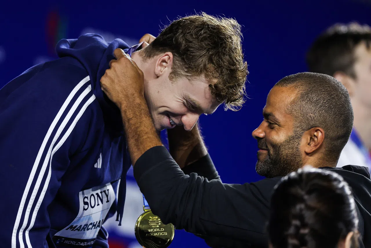 在男子200米混合泳颁奖仪式上，NBA圣安东尼奥马刺名宿帕克（右）惊喜现身，为包括同胞马尔尚（左）在内的三人佩戴奖牌。（白艳琳摄）