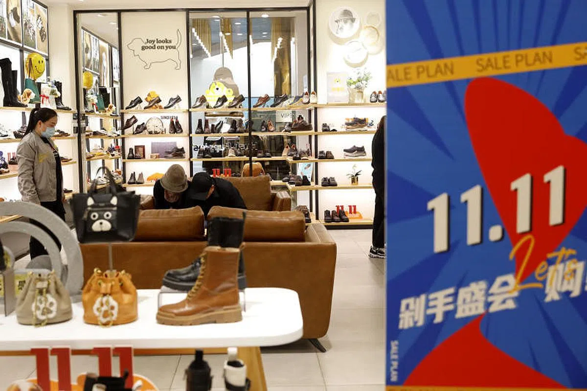 云南省昆明市一些商家11月11日推出线下“双十一”促销活动，吸引消费者。一名顾客在实体店里挑选心仪的鞋子。（中新社）