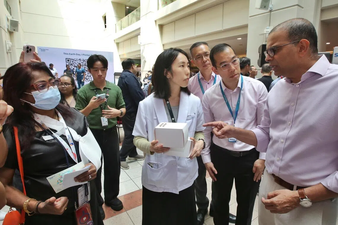 永续发展与环境部高级政务部长普杰立（右一）在参加推介活动时，听陈笃生医院医疗人员介绍纯纸质药盒。（特约陈福洲摄）