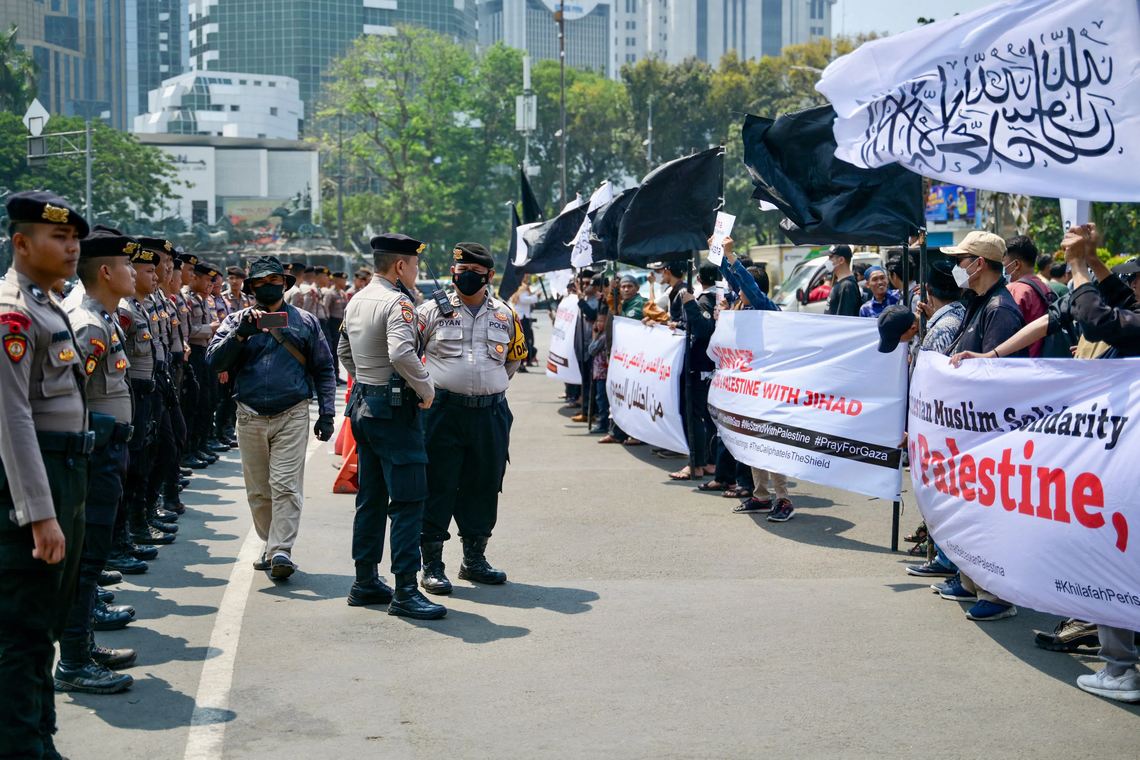 10月13日，印度尼西亚首都雅加达出现声援巴勒斯坦的集会，警方筑成人墙防止示威活动恶化。（法新社）