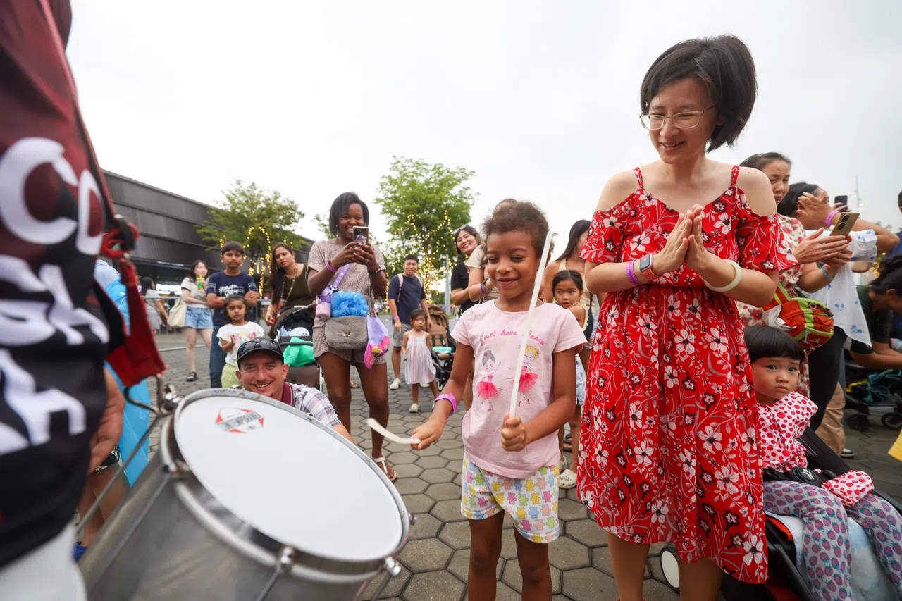 来自Bloco Singapura鼓团的乐手在新加坡体育城首届跨年倒数派对上演出，吸引孩童和家长驻足聆听互动。（吴先邦摄）