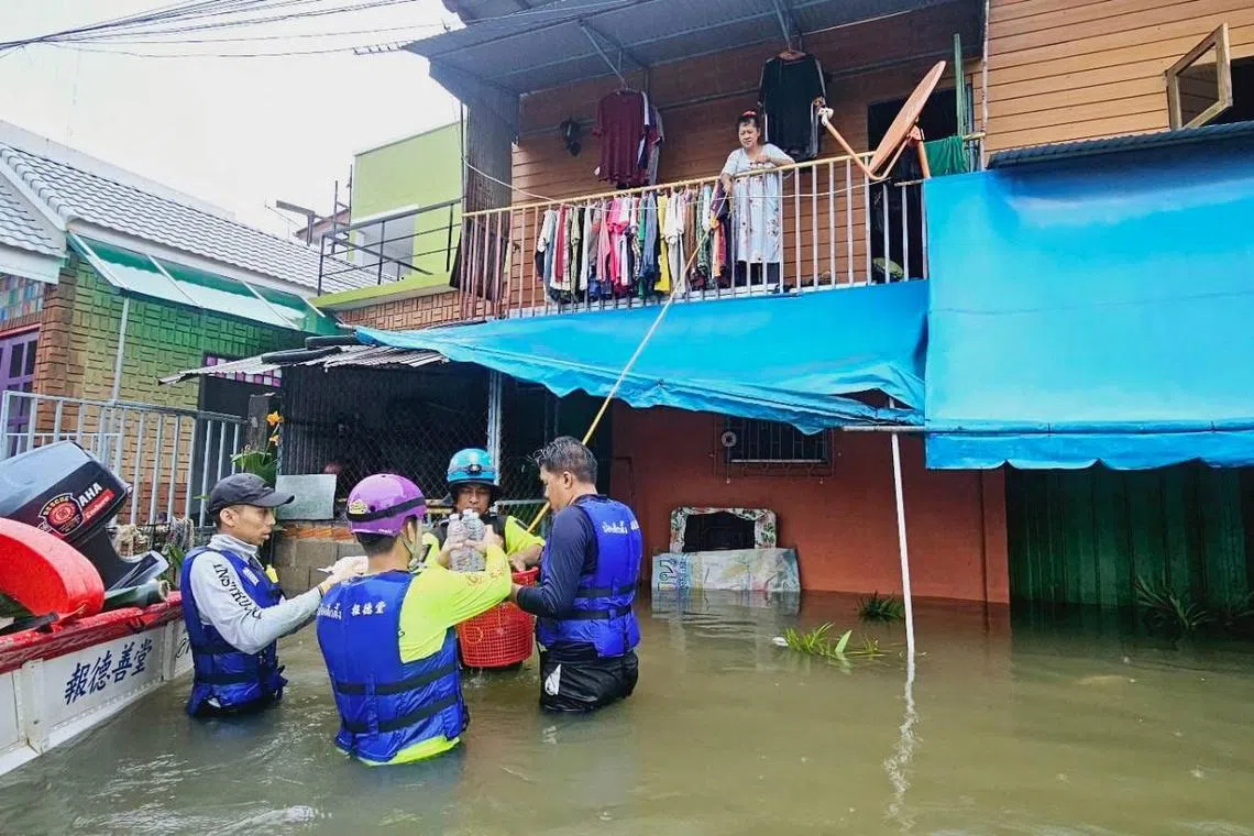 在泰国南部也拉府，许多房屋被洪水包围，民众躲到二楼避难，救援人员用吊篮将瓶装水等物资送到他们手上。（路透社）